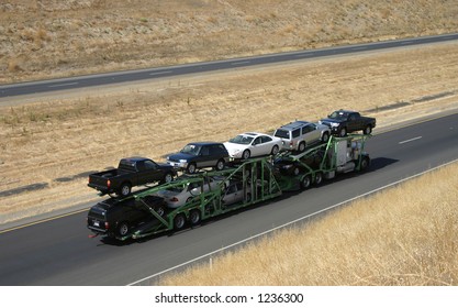 A large truck delivers new cars via highway.