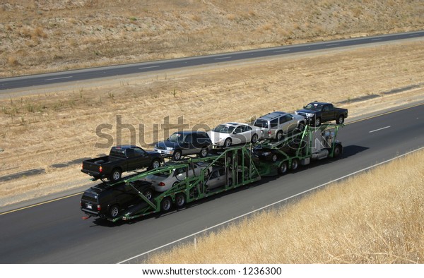 A large truck\
delivers new cars via\
highway.
