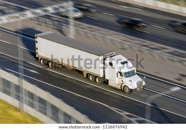 Large\
truck with a trailer on the highway at a speed that moves along the\
asphalt, evening sunset light. View from\
above