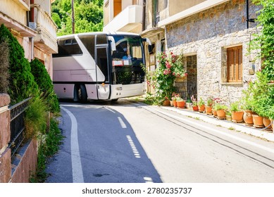A large type bus is making a tight turn on a very narrow street in a village on Crete