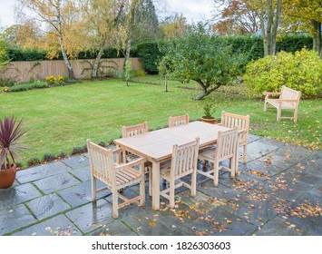 Large UK Back Garden In Autumn With Wooden Furniture On A Garden Patio Terrace