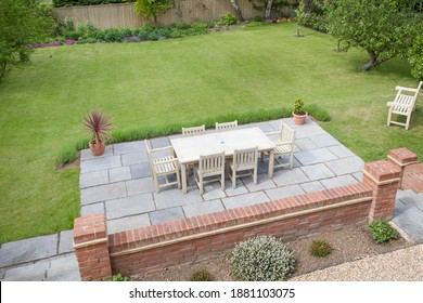 Large UK back garden with lawn and wooden patio furniture on a terrace in summer - Shutterstock ID 1881103075