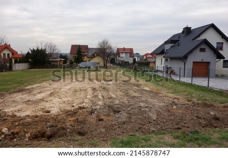 A large undeveloped plot of land, next to single-family houses at the end of the city