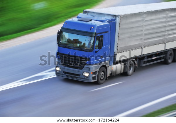 large van with  load\
moves along  road