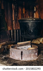 A Large Vat In Which Cheese Is Cooked Over An Open Fire. The Black Cauldron Is Prepared Over An Open Wood Fire. Cheese Factory In The Mountains.