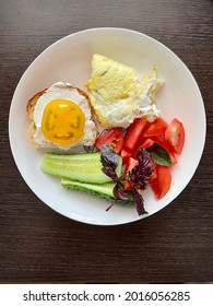 large vertical photo. breakfast. healthy food. scrambled eggs with fresh vegetables and basil on a white plate. top view close-up.