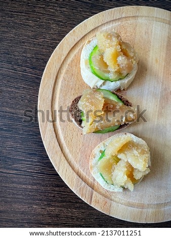 large vertical video. top view of a wooden board with small sandwiches. Herring caviar with cucumber slice on a piece of light and dark baguette. Source of omega-3. healthy snack. eco.