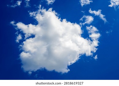 large volumetric white cloud is located in the center of the frame surrounded by clear blueness on a clear day