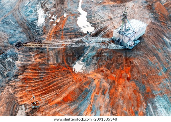 A large\
walking excavator works in a quarry for the extraction of rare\
metals. Drone view. Industrial\
landscape.