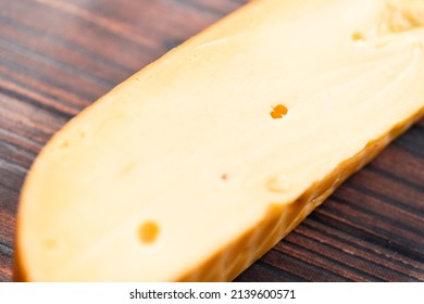 Large Wedge Of Smoked Gouda Cheese On A Dark Wooden Background.