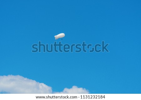 Large white air balloon in the shape of an airship in the blue sky