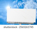 A large, white blank billboard or promotion poster is displayed outdoors, situated prominently in an open area. The billboard is vast, featuring a clean, flat white surface with no text