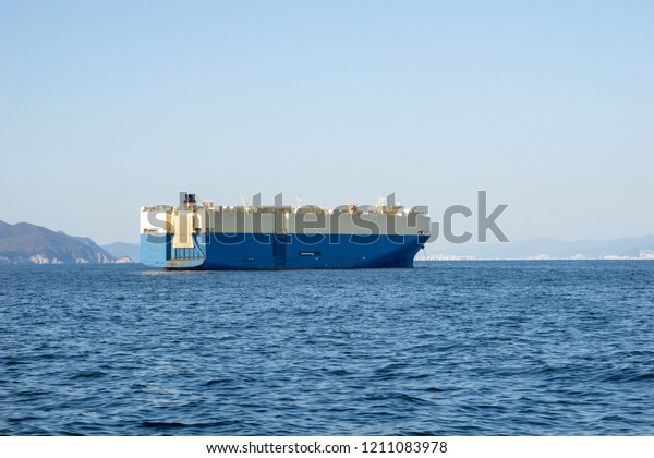 Large White and blue Roll-on/roll-off (RORO or\
ro-ro) ships or oceangoing vehicle carrier ship anchor in the open\
sea. Roro ship designed to carry wheeled cargo such as cars,\
trucks, trailers, etc.