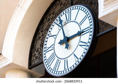 Large White Clock With Black Hands And Roman Numerals Close-up On The Facade Of The Building. The Passage Of Time