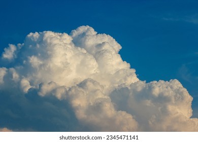 A large white cloud in a blue sky. The cloud is fluffy and round, and it takes up most of the sky. The sky is a deep blue color, and it is clear except for the cloud.