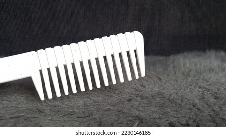 A large white comb is used as an object with a black background