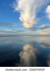 Large White Evening Clouds Reflecting Onto Still Water