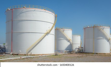 large white Industrial tanks for petrol and oil with blue sky.Fuel tanks at the tank farm. metal stairs on the side of an industrial oil container.Staircase on big fuel tank