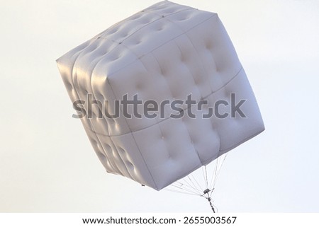 large white inflatable cube floating against a pale overcast sky backdrop