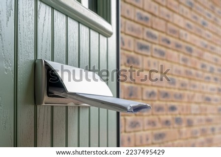 large white letter half pushed into the letter postal box of a domestic house front door