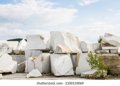 Large white marble stones in an old abandoned quarry. White marble texture. Smooth cuts on the rocks. The marble quarry is horizontal.