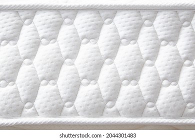 Large white mattress with stitched finishing lines. Close-up. Side view. Copy space.