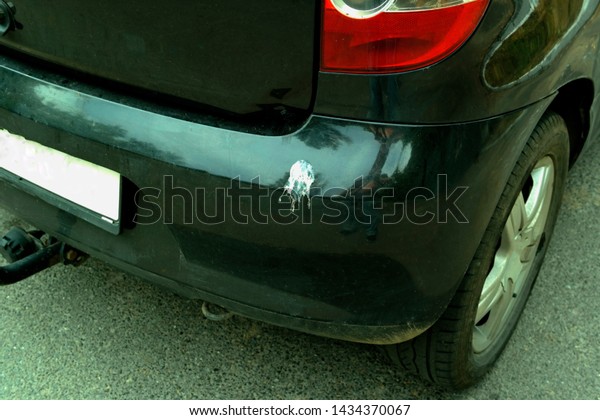 A large white spot from bird excrement\
on the black bumper of the car.Dirty bird\
car
