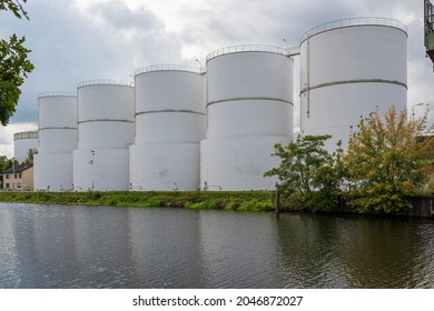 Large White Steel Reservoirs Of A Tank Farm For Mineral Oil At A Canal. 