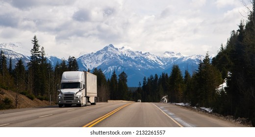 large white transport truck travelling on trans Canada highway in British Columbia Canada with scenic mountains mountaineous scenery in background good winter road conditions horizontal format  - Shutterstock ID 2132261557