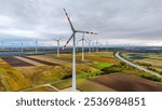 Large wind turbines with blades in field aerial view bright orange sunset. Windmills farm for energy production on beautiful Sunny day, generating