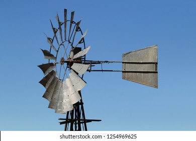 Large windmill windpump head and tail with blue sky background.