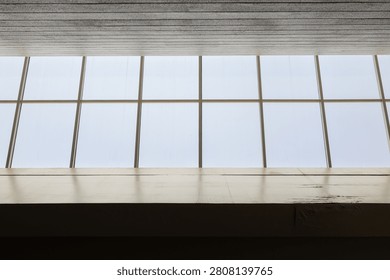 Large window with grid lines shows bright sky. Clean white frame contrasts with textured ceiling. Minimalist composition creates calm, open atmosphere. Ideal for themes like architecture, design