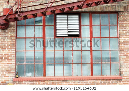 A large window and red fire escape on a red brick building in the warehouse district of New Orleans