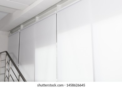 Large window with white roller blinds indoors