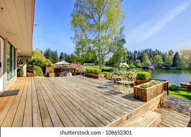 Large Wood Deck Near House With Lake And Spring Landscape.