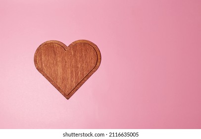 A Large Wooden Heart Of Dark Brown Color On A Pink Background. Template. Mock Up. Top View