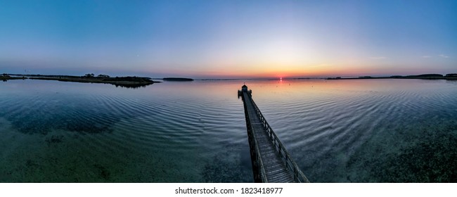 Large wooden pier on a beach by sunset, aerial 180 degree view. - Powered by Shutterstock