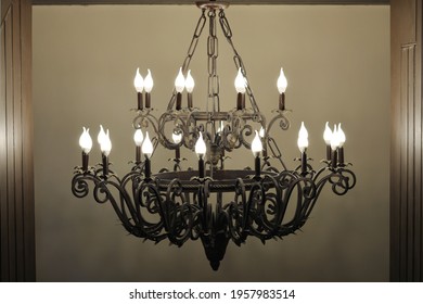 A Large Wrought Iron Chandelier Hangs On Chains.