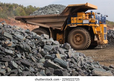 Large yellow dump trucks engaged in the transportation of rock mass in the quarry for mining. Machinery and equipment for iron ore mining - Shutterstock ID 2250222725