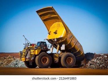 Large yellow haul truck tips load in open cast mine in Australia.