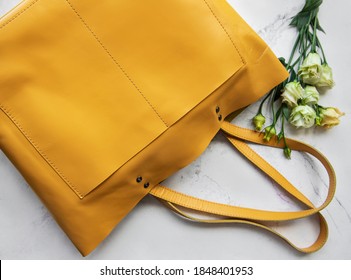 Large Yellow Leather Bag And Flowers On Marble Background