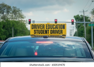 large yellow student driver sign on top of car at stoplight