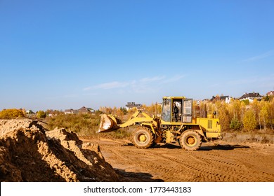 large yellow wheel loader aligns a piece of land for a new building. Preparation of the land for the auction. Leveling the landscape and adding sand for construction. Banner wallpaper.