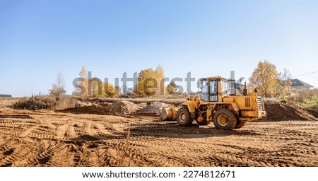 Large yellow wheel loader aligns plot of land for a new building. Land preparation for the auction. Leveling of territory and adding sand for construction site. Banner. Copy space. Special transport.