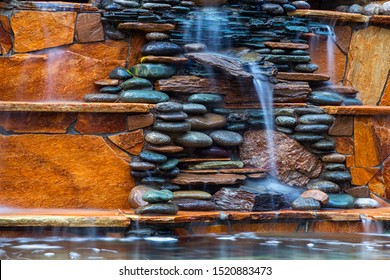 Larger plan A beautiful fountain, made of different stones, water flows from several clay jugs into a large pool with clear water. Pacifying picture of running water