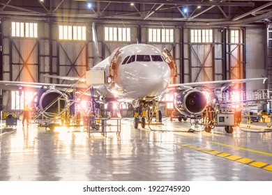 Large-scale inspection of all aircraft systems in the aircraft hangar by worker mechanics and other specialists. Bright light outside the garage door - Powered by Shutterstock