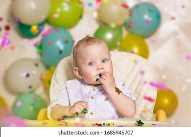 Large-scale portrait of a baby boy at a birthday party. Confetti from firecrackers and balloons around.