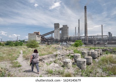 The Largest Air Pollutant In Dnipro Ukraine Is A Coke Chemical Plant. Flue Gas Stacks Emit Hundreds Of Tons Of Harmful Substances For Years Into The Atmosphere. Overweight Lady Goes By The Wasteland.