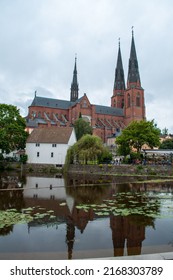 The largest cathedral in Sweden in the city of Uppsala in northern Europe. The red brick cathedral is reflected in the water.