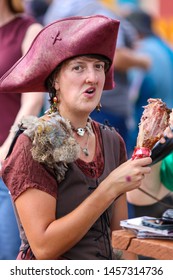 Larkspur, Colorado / USA - July 14, 2019:  Woman Eating A Turkey Leg At The Colorado Renaissance Festival Dressed In Historical Cosplay Outfit  